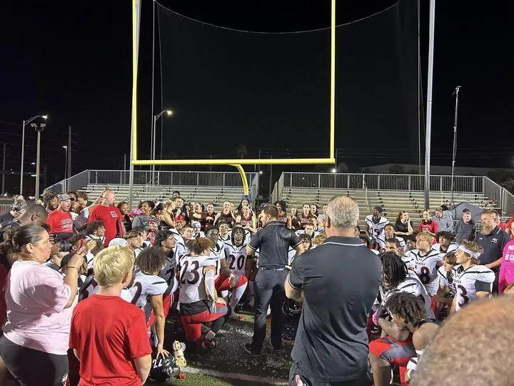 Black and red football helmet resting on the field under stadium lights