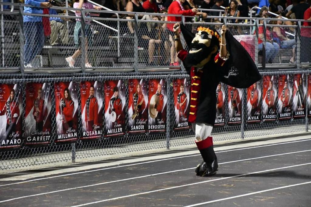 The Port Charlotte Pirate mascot waving a flag along the track at a night game